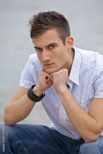 Photo: ernst schauender junger Mann sitzt am Flussufer ernst schauender junger Mann sitzt am Flussufer