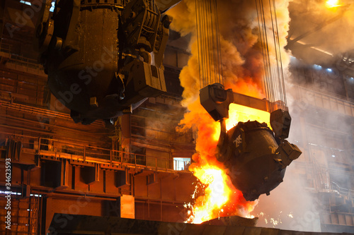 Photo: Smelting metal in metallurgical plant. Liquid iron from ladle Smelting metal in metallurgical plant. Liquid iron from ladle