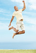 Excited young man jumping in joy against sky