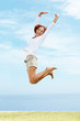 Photo: Excited young woman jumping on green grass Excited young woman jumping on green grass