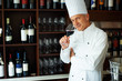 Handsome cook tasting red wine