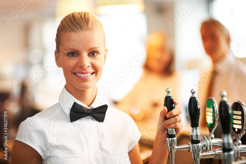 Foto: Beautiful young bartender smiling at work Beautiful young bartender smiling at work