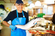Happy man holding fresh dead fish in his store