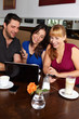 Gruppe mit Netbook und Handys im Café