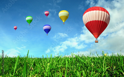 Photo: Hot air balloons floating over green field Hot air balloons floating over green field