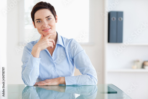 Photo: Smiling Businesswoman sitting behind a desk Smiling Businesswoman sitting behind a desk