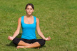 Pretty young woman meditating on grass
