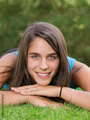 Photo: Cute young woman lying on grass in the park Cute young woman lying on grass in the park