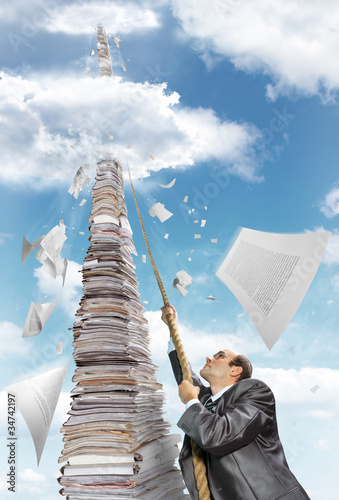 Photo: Businessman climbing up the pile of paperwork Businessman climbing up the pile of paperwork