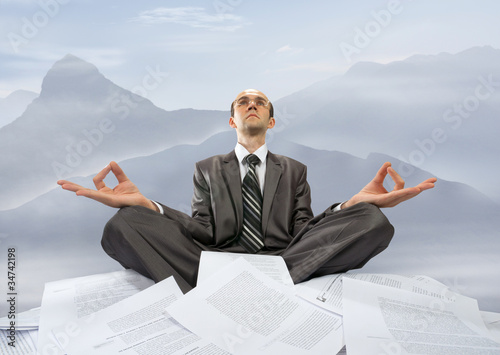 Foto: Businessman meditating in mountains Businessman meditating in mountains
