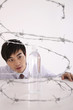Man looking at plastic water bottle inside coiled barbed wire