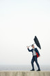 Businessman with an umbrella, wind blowing his umbrella away