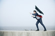 Businessman with an umbrella, wind blowing his umbrella away