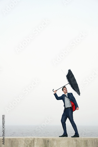 Photo: Businessman with an umbrella, wind blowing his umbrella away Businessman with an umbrella, wind blowing his umbrella away