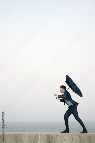 Photo: Businessman with an umbrella, wind blowing his umbrella away Businessman with an umbrella, wind blowing his umbrella away