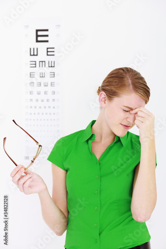 Photo: Businesswoman holding her glasses and massaging her temple Businesswoman holding her glasses and massaging her temple