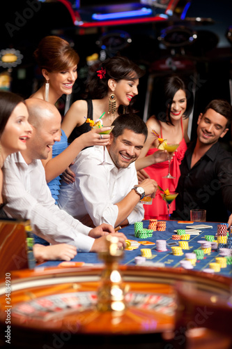 Photo: happy caucasian friends playing roulette in casino happy caucasian friends playing roulette in casino