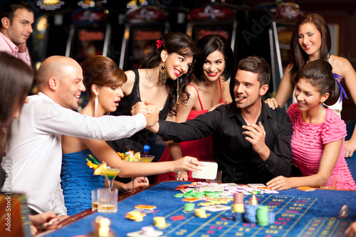 Photo: happy caucasian friends playing roulette in casino happy caucasian friends playing roulette in casino