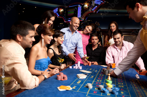 Foto: happy friends playing roulette in a casino happy friends playing roulette in a casino