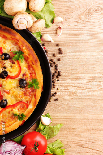 Photo: tasty pizza with olives and vegetables on a wooden background tasty pizza with olives and vegetables on a wooden background