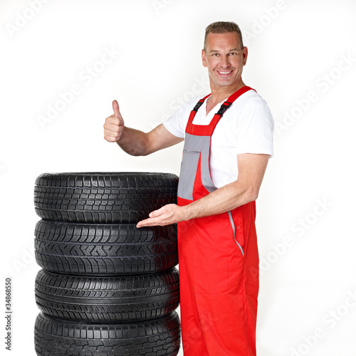 Foto: Master mechanic is proud of his winter tires and shows thump up Master mechanic is proud of his winter tires and shows thump up