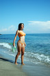 Woman in orange bikini on the shoreline