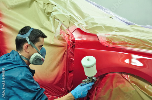 Photo: Worker painting a car. Worker painting a car.
