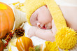 Newborn kid among pumpkins