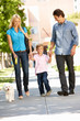 Family walking with dog in city street