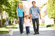 Family walking with dog in city street