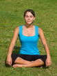 Pretty young woman meditating on grass