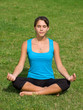 Pretty young woman meditating on grass