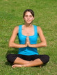 Pretty young woman meditating on grass