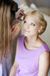 Foto: Young beautiful bride applying wedding make-up by make-up artist Young beautiful bride applying wedding make-up by make-up artist
