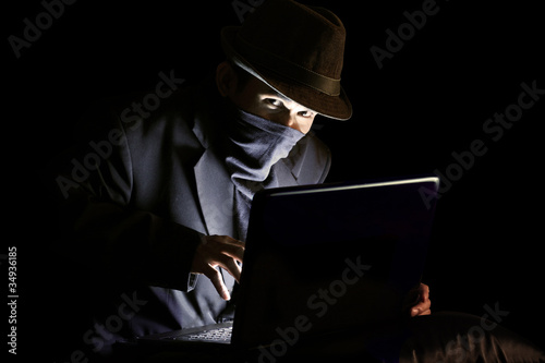 Photo: Masked man stealing sensitive information Masked man stealing sensitive information