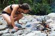 Young woman making a fire on pebble beach