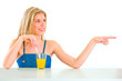 Photo: Cheerful teenager with orange juice pointing in corner Cheerful teenager with orange juice pointing in corner