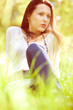 Photo: Thoughtful pretty girl sitting on green grass Thoughtful pretty girl sitting on green grass