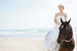 Beach wedding: bride on a horse by the sea