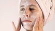 Joven tres cuartos de perfil aplicando crema para cuidado facial