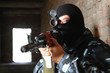 Armed soldier in black mask targeting with a gun