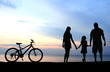 Mother and kids silhouettes on beach at sunset Mother and kids silhouettes on beach at sunset