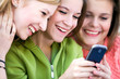 Photo: Three girls looking at mobile phone Three girls looking at mobile phone