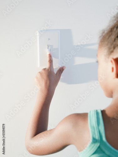 Photo: Mixed race girl turning off light Mixed race girl turning off light