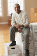 African man sitting on moving boxes