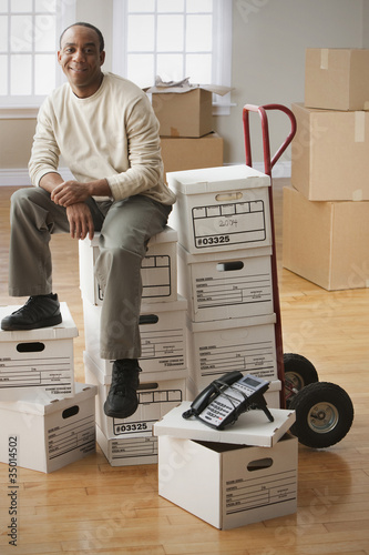 Photo: African man sitting on moving boxes African man sitting on moving boxes