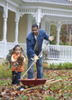 Black father and daughter raking leaves