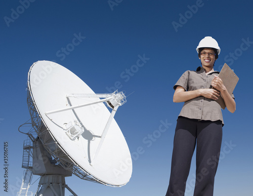 Foto: Mixed race businesswoman standing near satellite dish Mixed race businesswoman standing near satellite dish