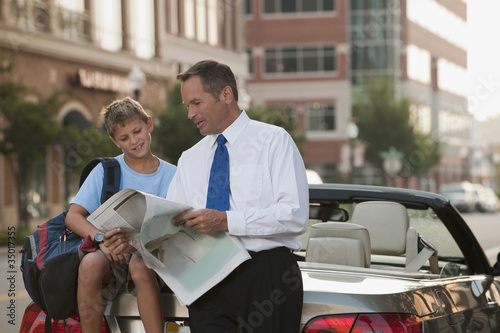 Photo: Caucasian businessman and son reading newspaper Caucasian businessman and son reading newspaper