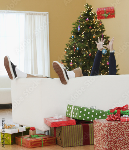 Photo: Mixed race boy laying on couch with Christmas gifts Mixed race boy laying on couch with Christmas gifts